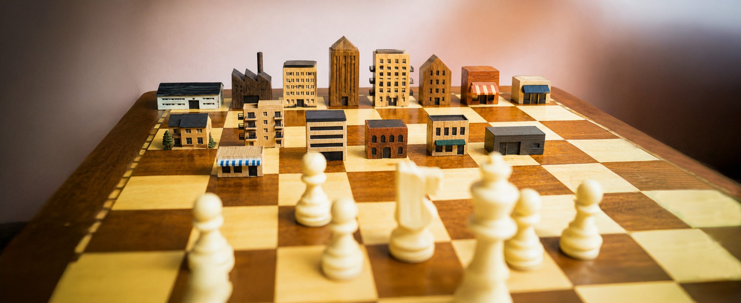 Wooden chess board with commercial buildings and white chess pieces